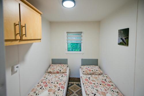 two beds in a small room with a window at MOLO RESORT KEMPING in Osiek