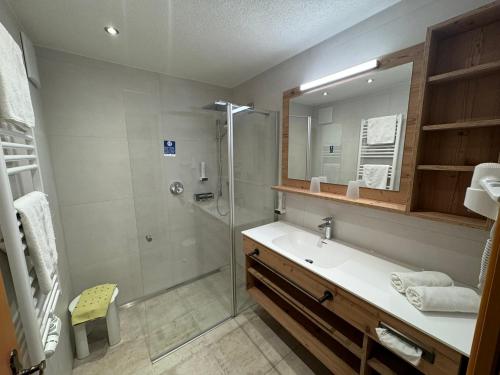 a bathroom with a shower and a sink and a mirror at Hotel Bergland in Lermoos