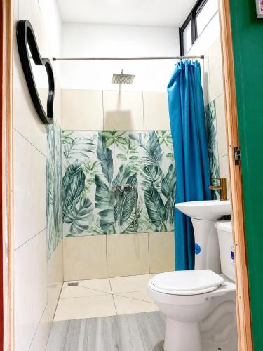 a bathroom with a toilet and a blue shower curtain at Jungle Serenity Haven in Cocles