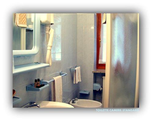 a white bathroom with a sink and a mirror at Hotel Beau Sejour in Etroubles