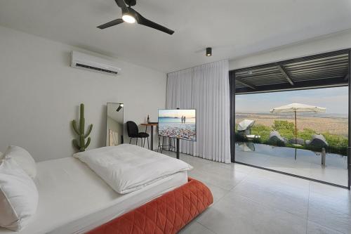 a bedroom with a bed and a view of the ocean at Y HOUSE SUITES in Mishmār Hāyardin