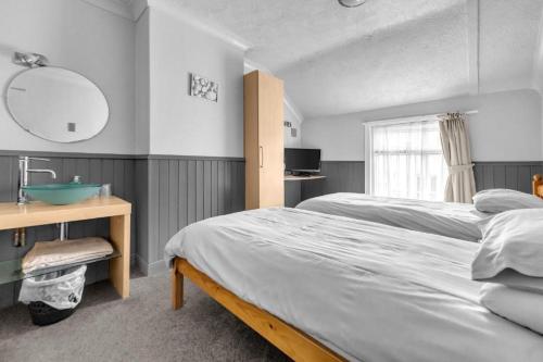 a bedroom with two beds and a sink and a mirror at Mallowview guest house in Cleethorpes