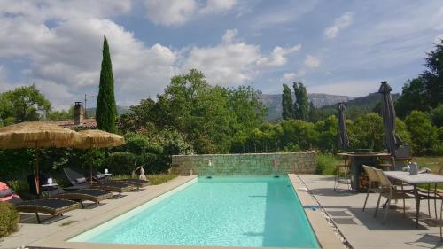 a swimming pool with chairs and a table and an umbrella at Villa dolce vita in Nans-les-Pins