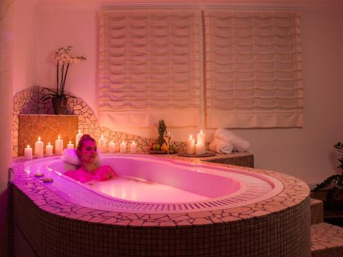 a woman laying in a bath tub with candles at Aktiv Panoramahotel Daniel in Sautens