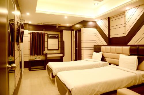 a hotel room with two beds and a bathroom at Hotel S G International in Dhanbād