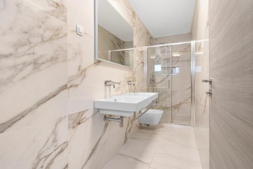 a white bathroom with a sink and a shower at Villa Viola in Lovran