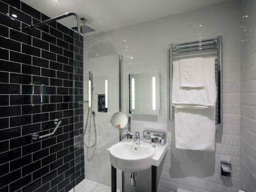 a white bathroom with a sink and a shower at Mercure Doncaster Centre Danum Hotel in Doncaster