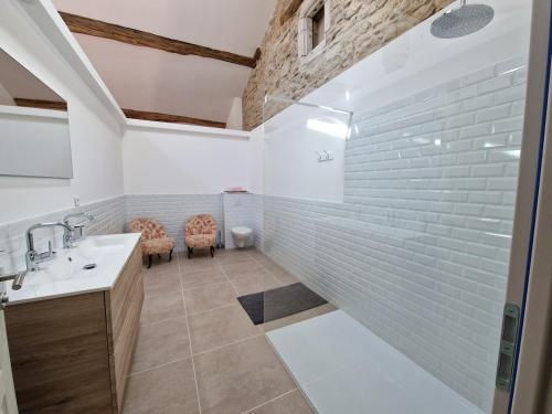 a bathroom with a sink and a shower with white tiles at La Ferme Duval in Vaudémont