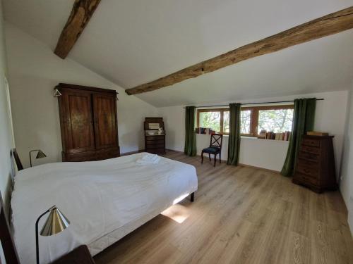 a bedroom with a large white bed and wooden floors at La Ferme Duval in Vaudémont