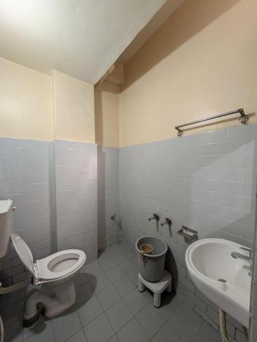 a bathroom with a toilet and a sink at Vinayaka Lodge in Bangalore