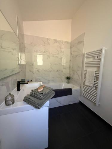 a white bathroom with a tub and a sink at Les Jujubiers in Draguignan