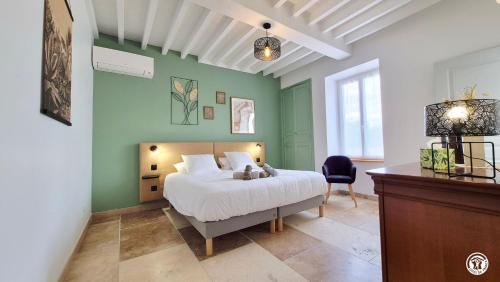 a bedroom with a white bed and green walls at Le Tarare in Guipy