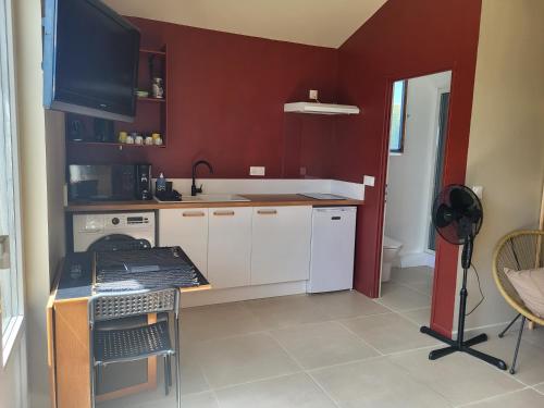 a kitchen with white cabinets and a tv on the wall at Studio Cosy in Saint-Lon-les-Mines