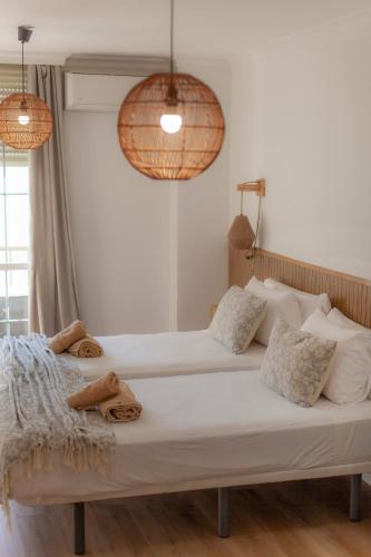 a bedroom with two beds and two pendant lights at Hostal San Miguel by Croma in Estepona