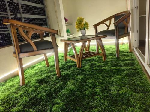 two chairs and a table in a room with grass at Cozy Crib Stays in Greater Noida