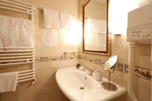 a white bathroom with a sink and a mirror at Garni Hotel Leopold I in Novi Sad