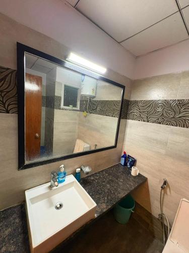 a bathroom with a sink and a large mirror at Cozy Crib Stays in Greater Noida