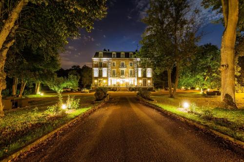 a large house with lights on a road at Logis Hôtel - Le Manoir de Sauvegrain in Saint-Lambert
