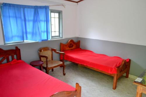a room with two beds and a chair and a window at Green Valley Holiday Resort in Haputale