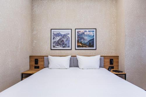 a bedroom with a large bed with three pictures on the wall at TAU 28 Hotel in Almaty