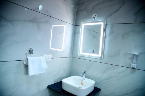 a white bathroom with a sink and two windows at Aldur Residency in Aldūr
