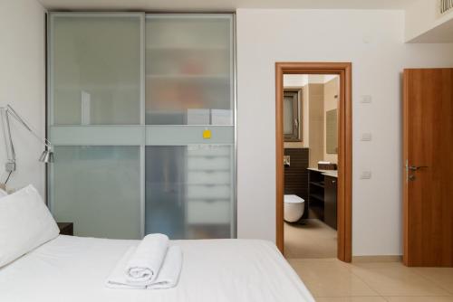a bedroom with a white bed and a bathroom at Mamad Comfort & Terrace In Ramat Aviv By Feelhome in Tel Aviv