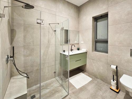a bathroom with a glass shower and a sink at Design & Balcony In City Center By Feelhome in Tel Aviv