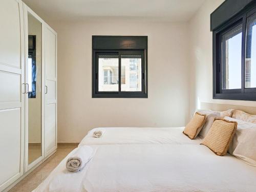 two beds in a room with two windows at Mamad Family Friendly New Condo By Feelhome in Yerushalayim