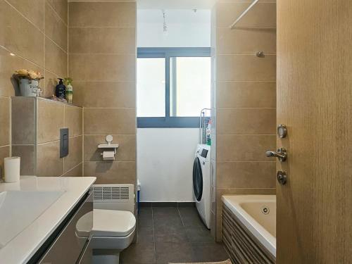 a bathroom with a toilet and a sink and a tub at Mamad Family Friendly New Condo By Feelhome in Yerushalayim