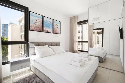 a white bedroom with a large bed and a window at Mamad New With Terrace Next To Park By Feelhome in Tel Aviv