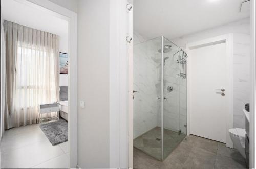 a white bathroom with a shower and a toilet at Mamad New With Terrace Next To Park By Feelhome in Tel Aviv