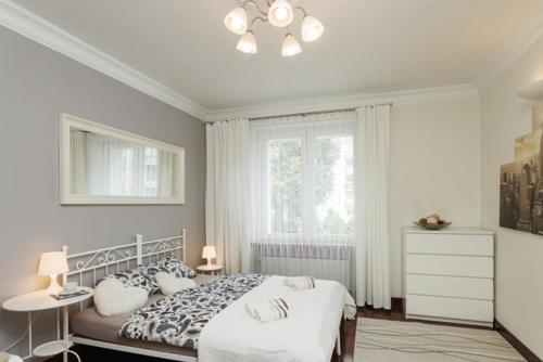 a white bedroom with a bed and a window at Apartament Abrahama in Gdynia