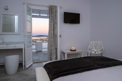 een slaapkamer met een bed, een tv en een raam bij Villa Irini in Naousa