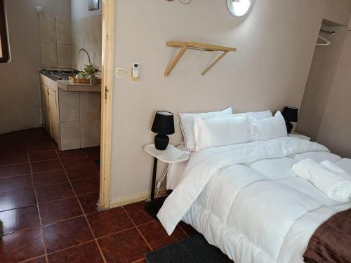 a bedroom with a bed with white sheets and a table at The Huts in Vila Praia Do Bilene