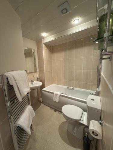 a bathroom with a toilet and a tub and a sink at Craigmonie Hotel Inverness by Compass Hospitality in Inverness