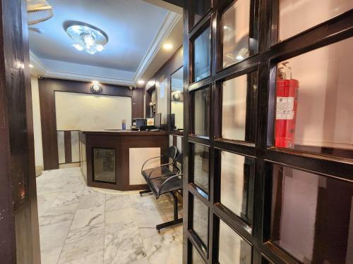 a lobby with a chair and a desk and window at Hotel Al Sana in Kolkata