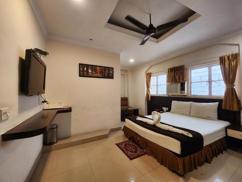 a bedroom with a bed and a flat screen tv at Hotel Al Sana in Kolkata