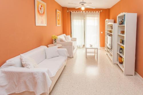 una sala de estar con muebles blancos y paredes de color naranja. en Apartamento Centro Jerez, en Jerez de la Frontera