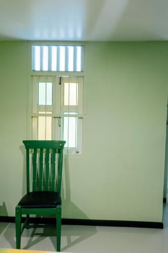 a green chair sitting in front of a window at Green Gallery Beach Boutique Hotel in Hua Hin