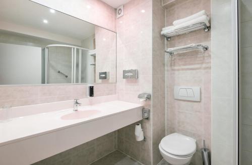 ein Badezimmer mit Waschbecken, Toilette und Spiegel in der Unterkunft Hotel Troja in Prag