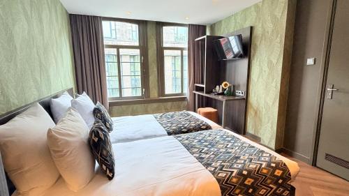 a bedroom with a bed with white pillows and a television at Hotel Damsquare in Amsterdam