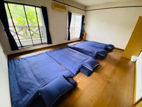 a large bed in a room with blue sheets at Guest House 楽風 in Anan