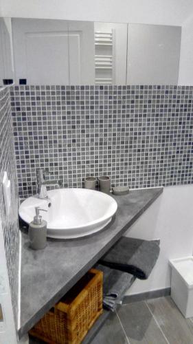 a bathroom with a sink and a mirror on a counter at Chambre d'Hôtes Les Macarons de Tata in Sainte-Eulalie