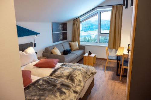 a living room with a couch and a bed in it at Chaletdorf-Fanningberg in Weisspriach