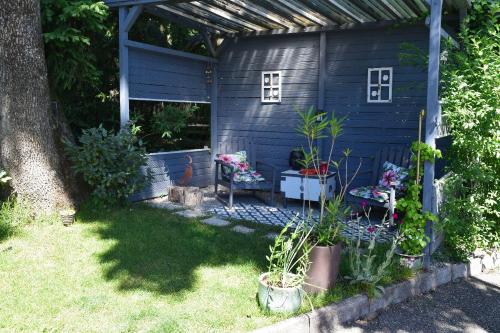a blue shed with two chairs and plants in a yard at Gite le GINKGO 50 M2 in Rougegoutte
