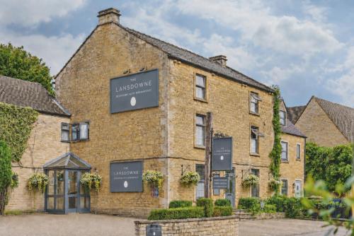 a large brick building with signs on the side of it at The Lansdowne Boutique Rooms with Breakfast - Adults Only in Bourton on the Water