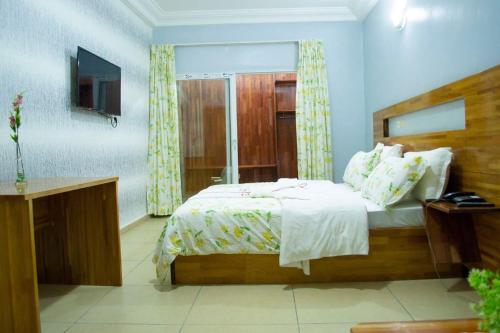 ein Schlafzimmer mit einem Bett und einem Fernseher in der Unterkunft Hôtel LEWI 2 Bouaké in Bouaké