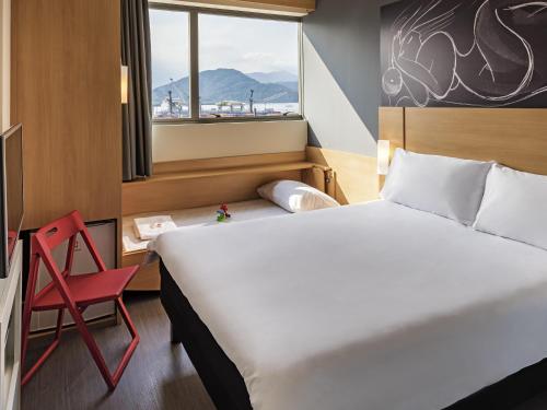 a hotel room with a bed and a red chair at ibis Santos Valongo in Santos