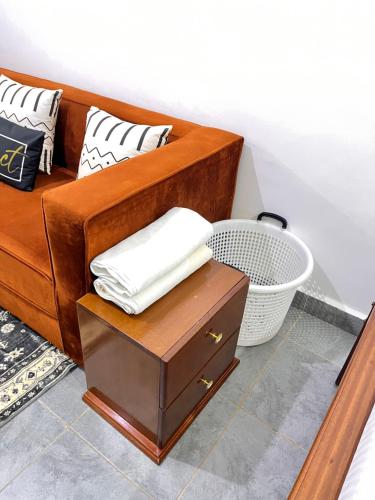 a wooden couch with white pillows and a basket at Casa Stays in Kiambu