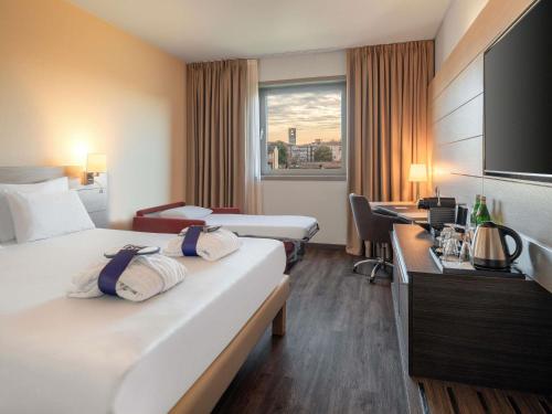 a hotel room with two beds and a window at Novotel Brescia Due in Brescia